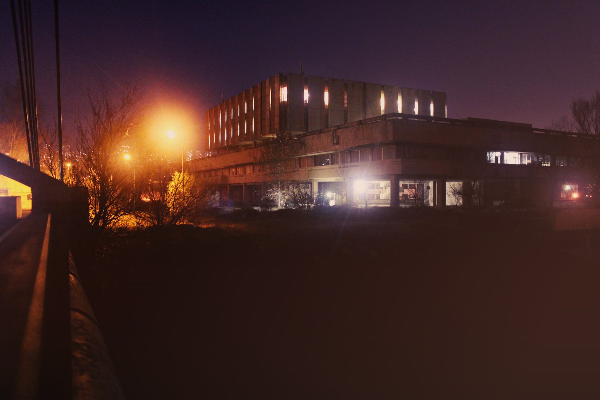 A dimly lit building stands out against a night sky, illuminated by streetlights, showcasing the beauty of man-made architecture in urban nightlife.