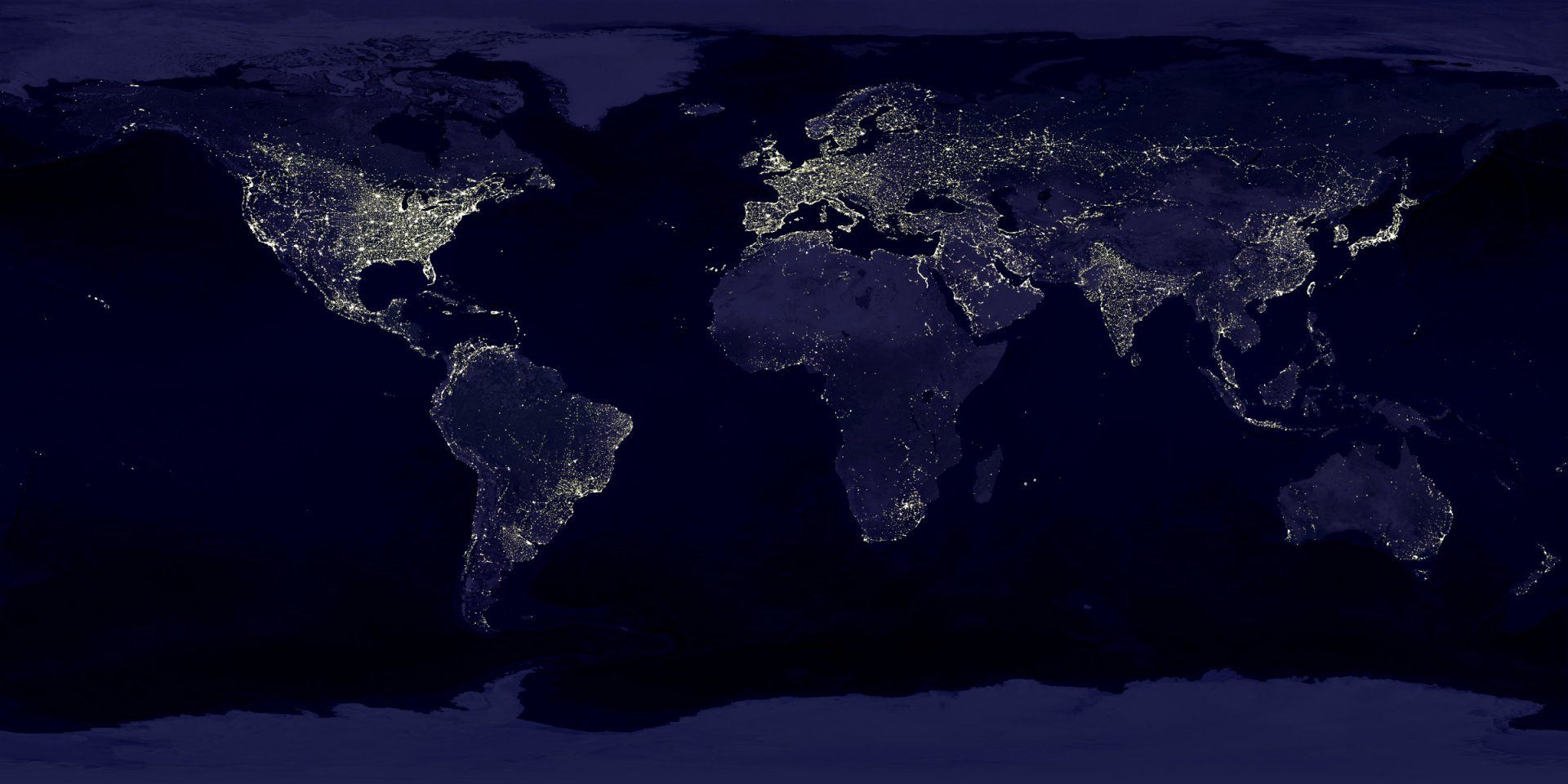 A nighttime view of Earth from space showing illuminated cities across continents, highlighting human presence within natural landmasses and oceans.