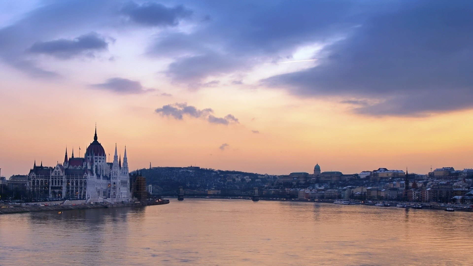 Sunset over the Danube in Budapest, with the man-made Hungarian Parliament building silhouetted against a pastel sky and the city skyline.
