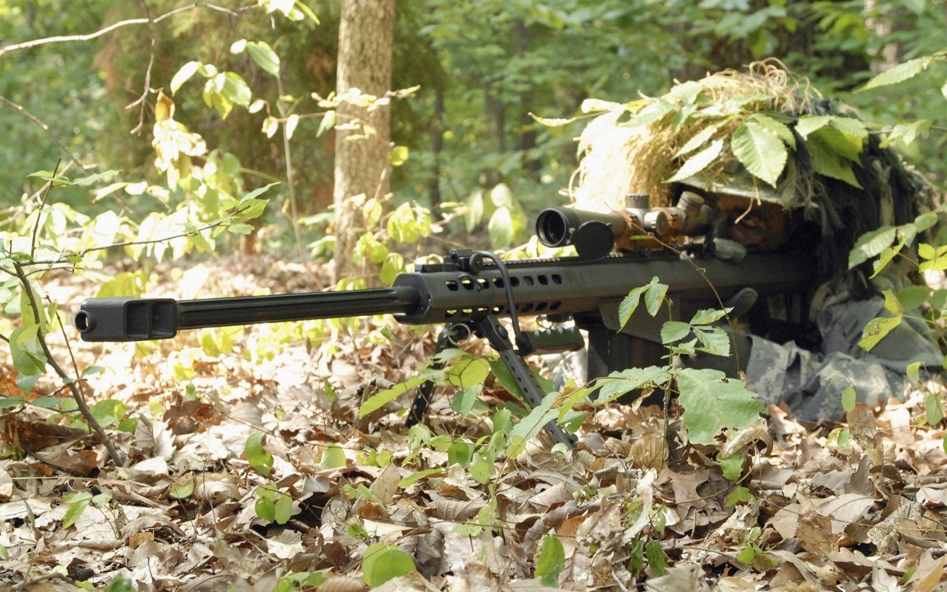 A military sniper is camouflaged among leaves and foliage, focusing intently through the scope of a rifle in a dense forest environment.