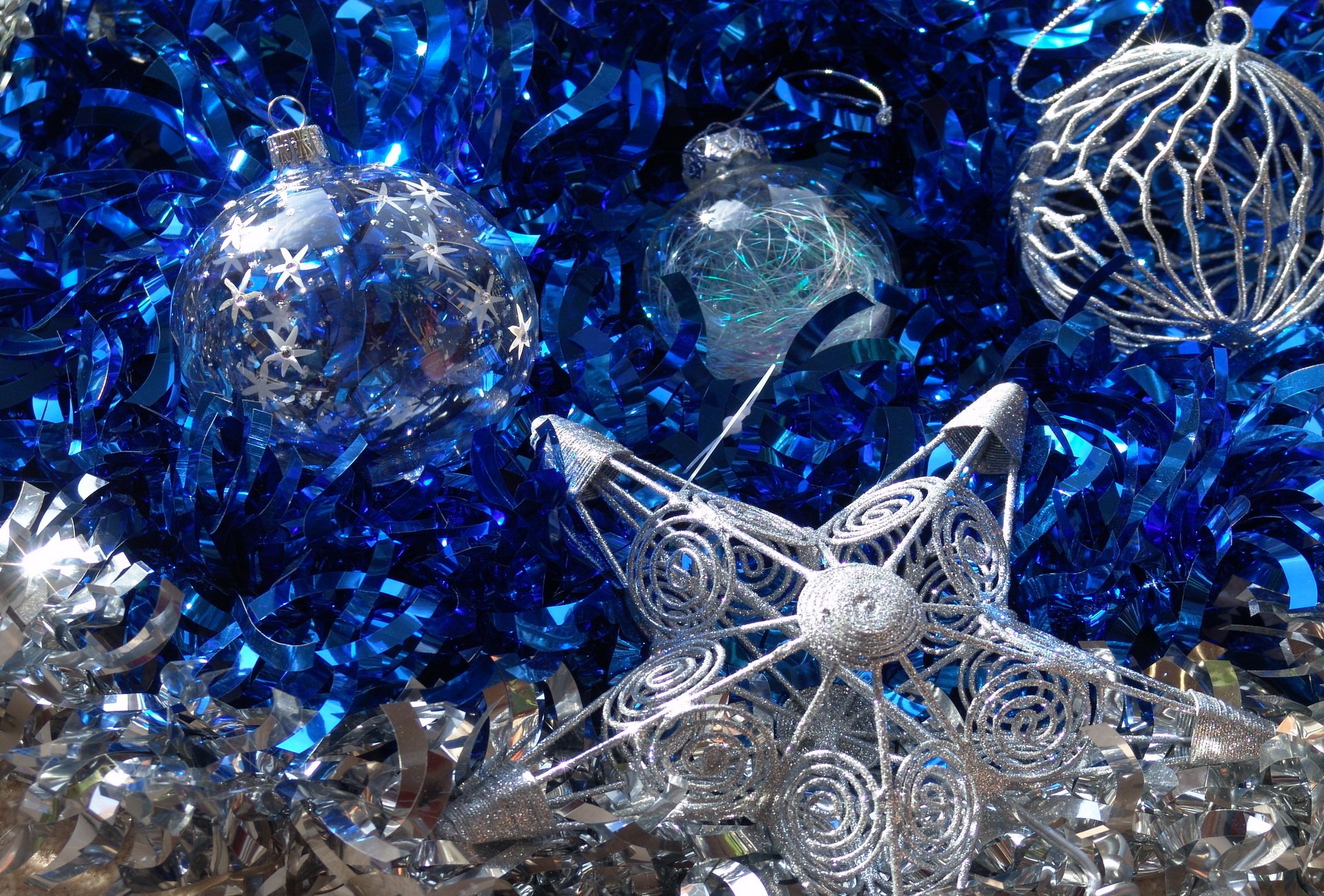 A festive arrangement featuring blue tinsel, shimmering silver decorations, and intricate ornaments, capturing the spirit of the Christmas holiday.