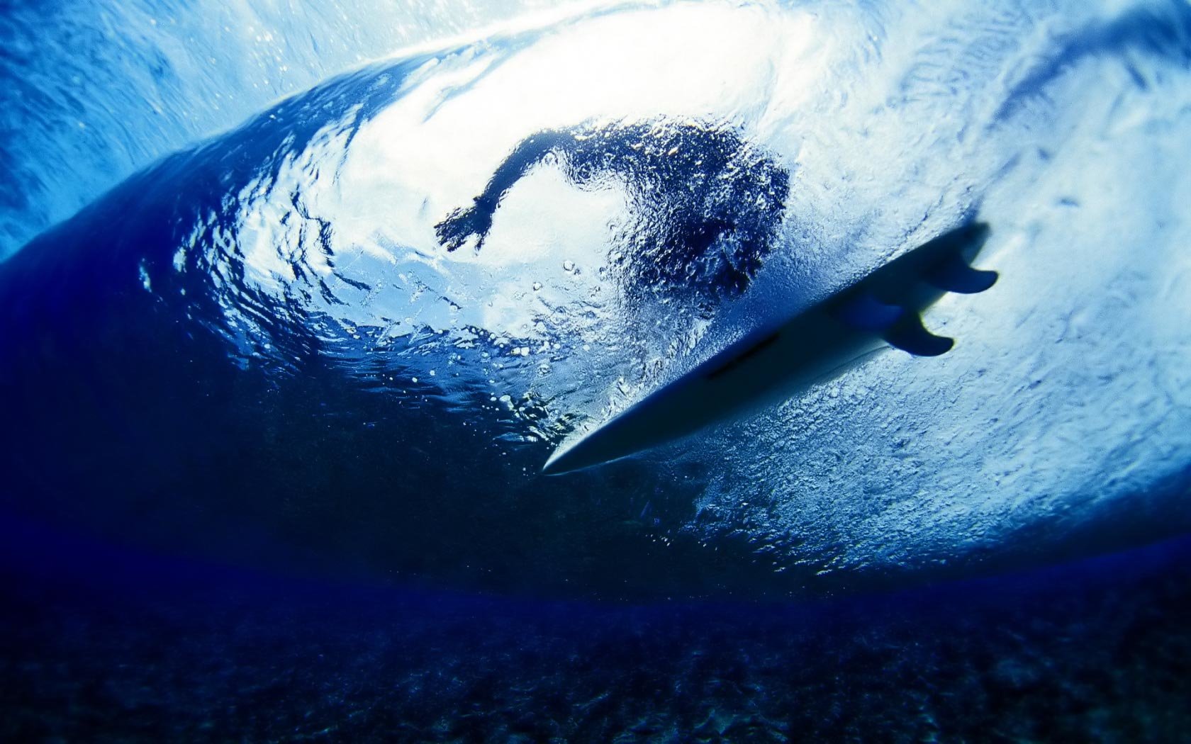 Surfer rides inside a large ocean wave, showcasing the thrill and skill of the sport of surfing.