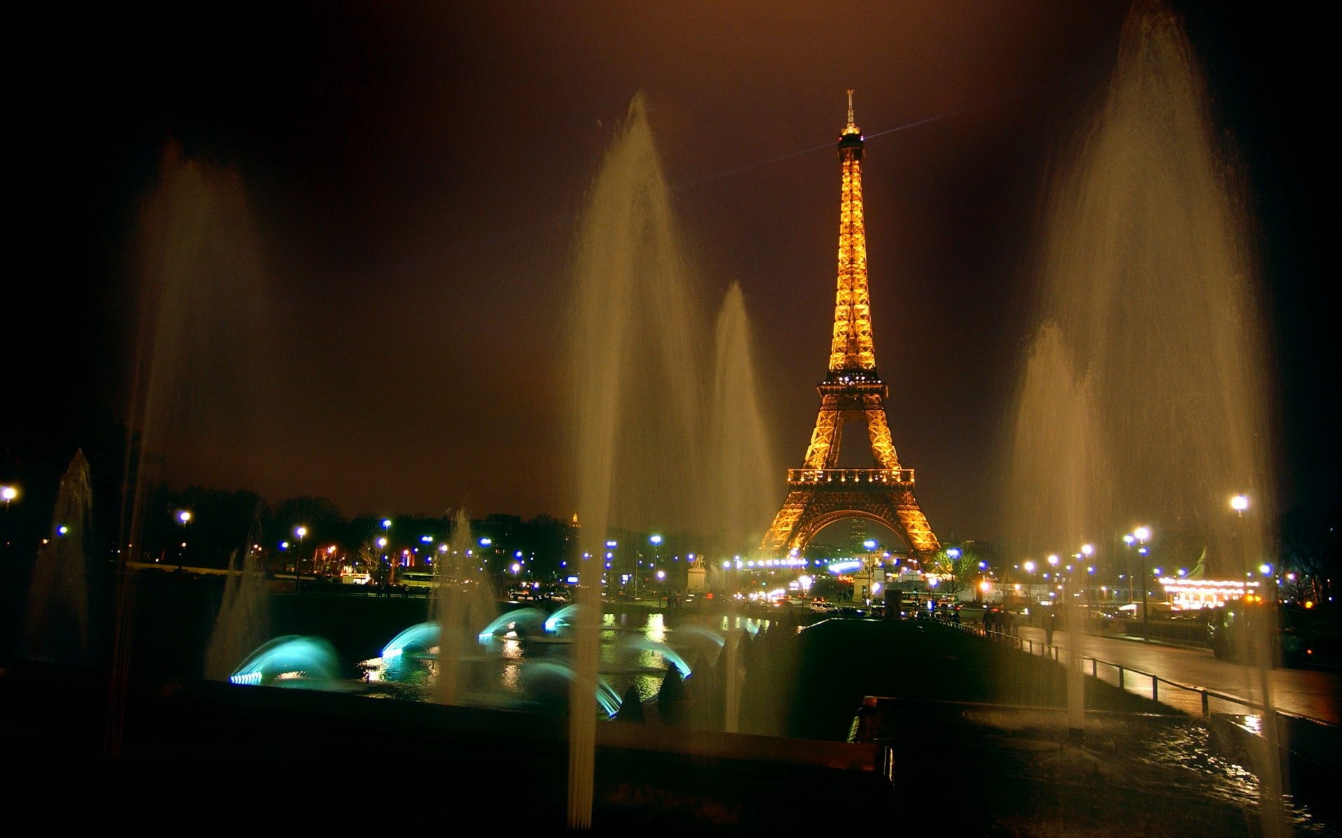 The Eiffel Tower illuminated at night, surrounded by dancing water fountains and vibrant lights, showcasing the beauty of this iconic man-made structure in Paris.