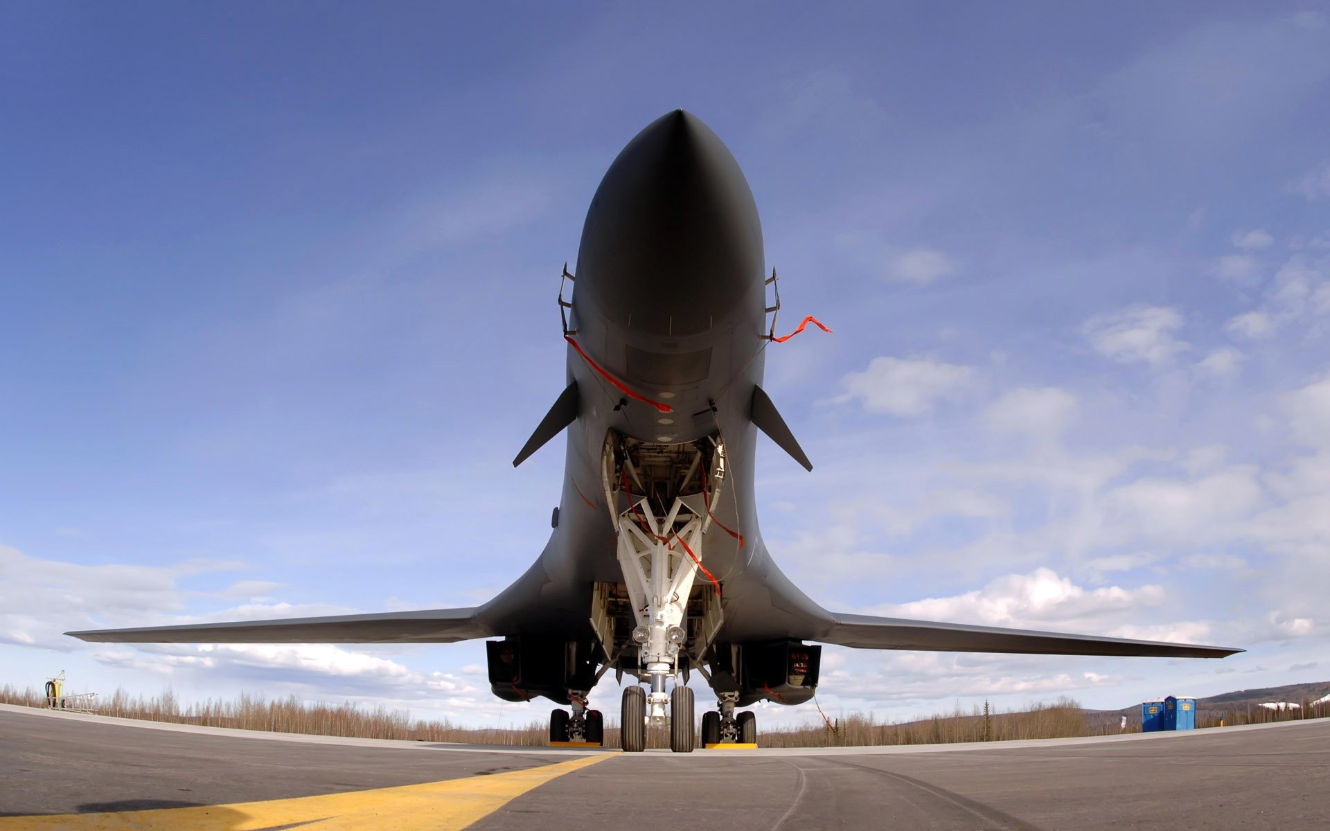 Rockwell B-1 Lancer military jet fighter parked on a runway under a blue sky with scattered clouds.