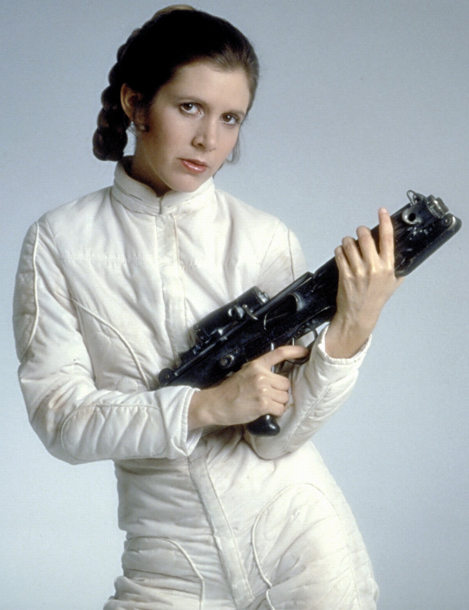A woman dressed in a white outfit holding a blaster gun, portraying a character from the Star Wars movie series.