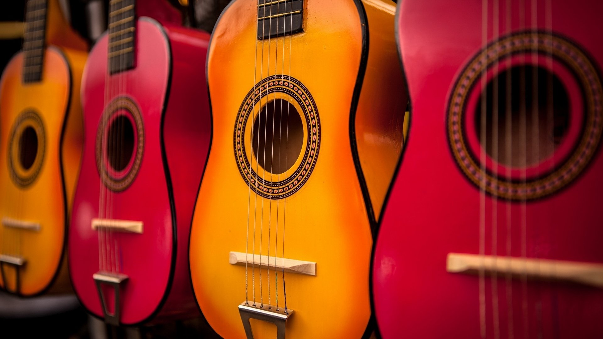 A vibrant display of guitars in shades of red and orange, showcasing their beautifully crafted designs, ready to create melodic music.