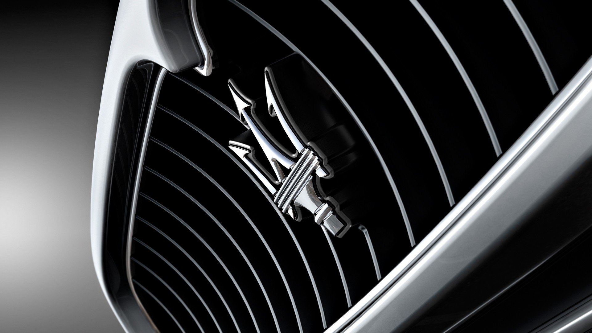 Close-up of a Maserati emblem, showcasing the iconic trident logo against a sleek, dark grille, emphasizing the brand's luxury and performance automotive aesthetic.