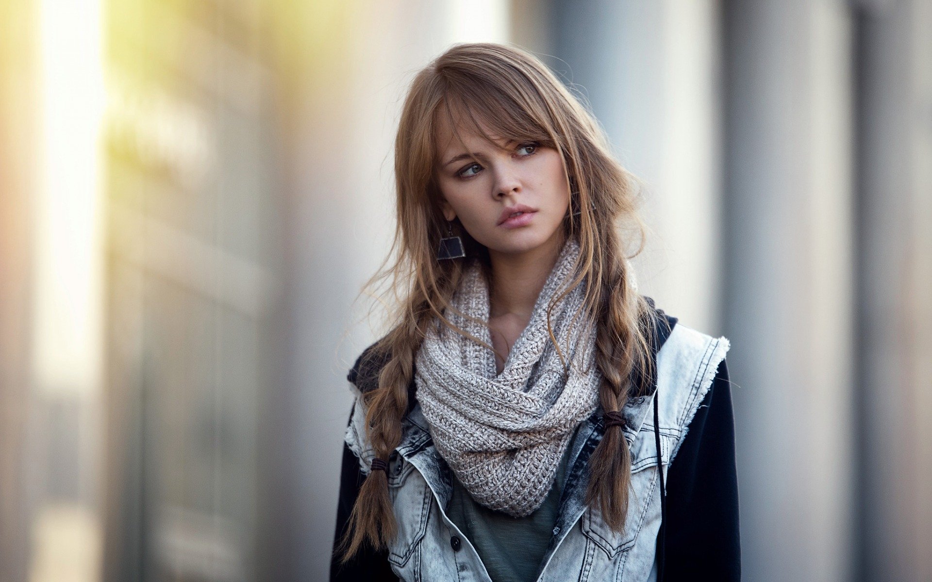A woman named Anastasiya Scheglova stands thoughtfully in a casual outfit, featuring a denim jacket and a cozy scarf, with soft lighting creating an atmospheric backdrop.