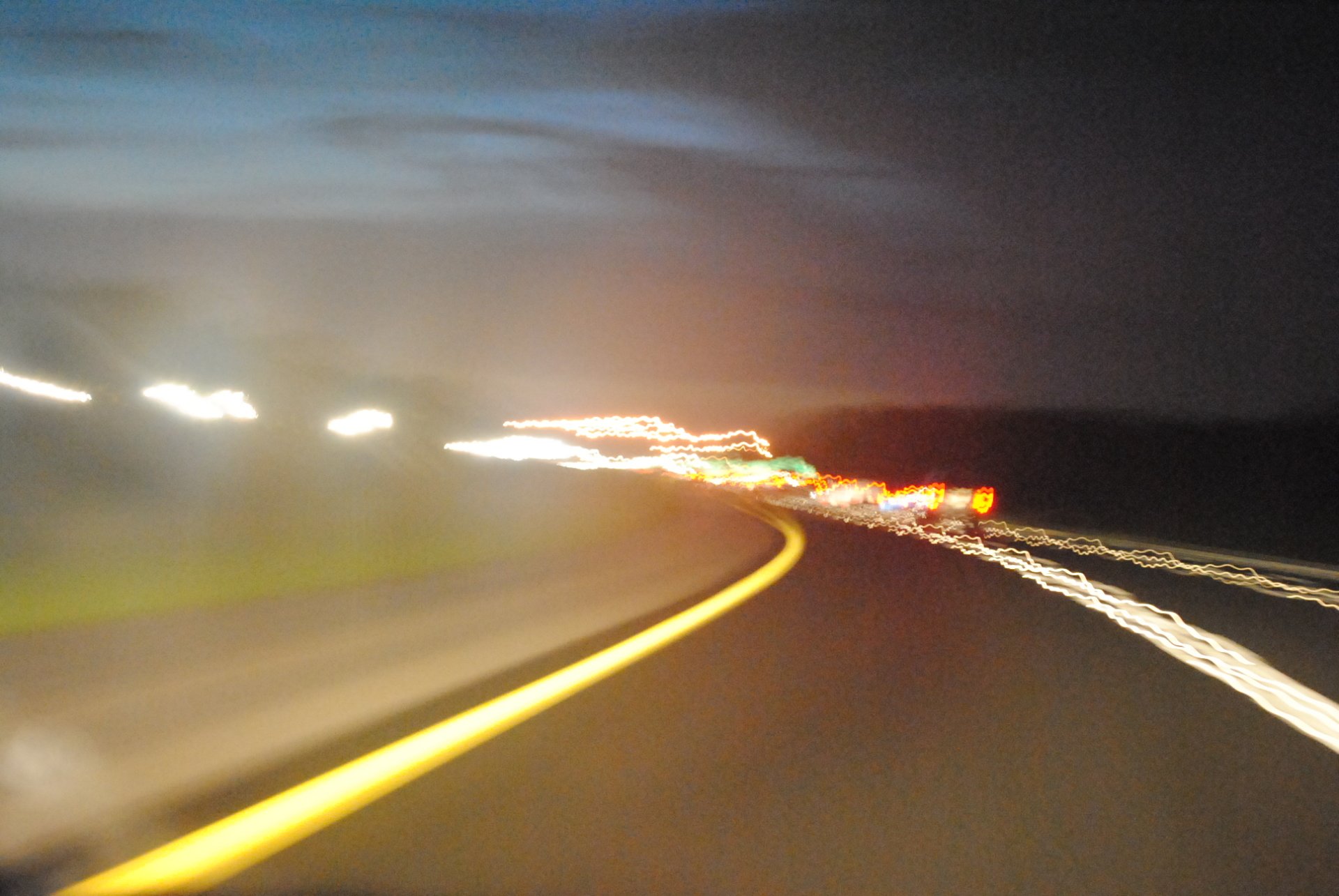 A long exposure photograph showcasing motion, with blurred lights and a winding road under a night sky, exemplifying dynamic manipulation in imagery.