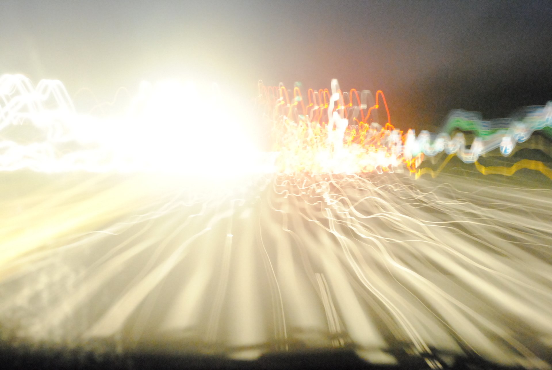 An abstract image showcasing vibrant light trails and manipulation, capturing the sensation of speed and movement on a dark roadway.