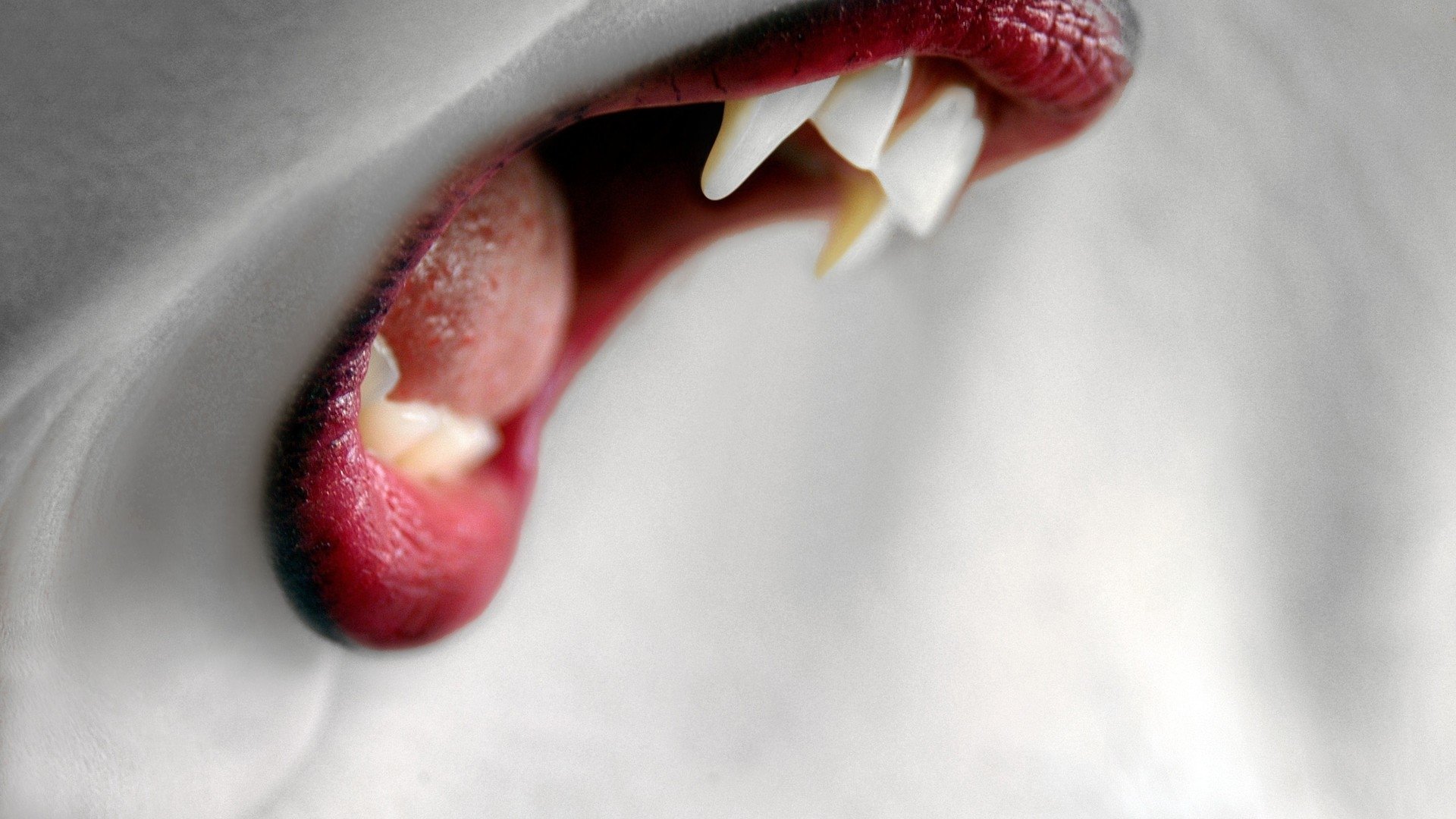 Close-up of a vampire's fangs, highlighted against a pale background, evokes a sense of fantasy and intrigue with their sharpness and the mysterious allure of the figure.