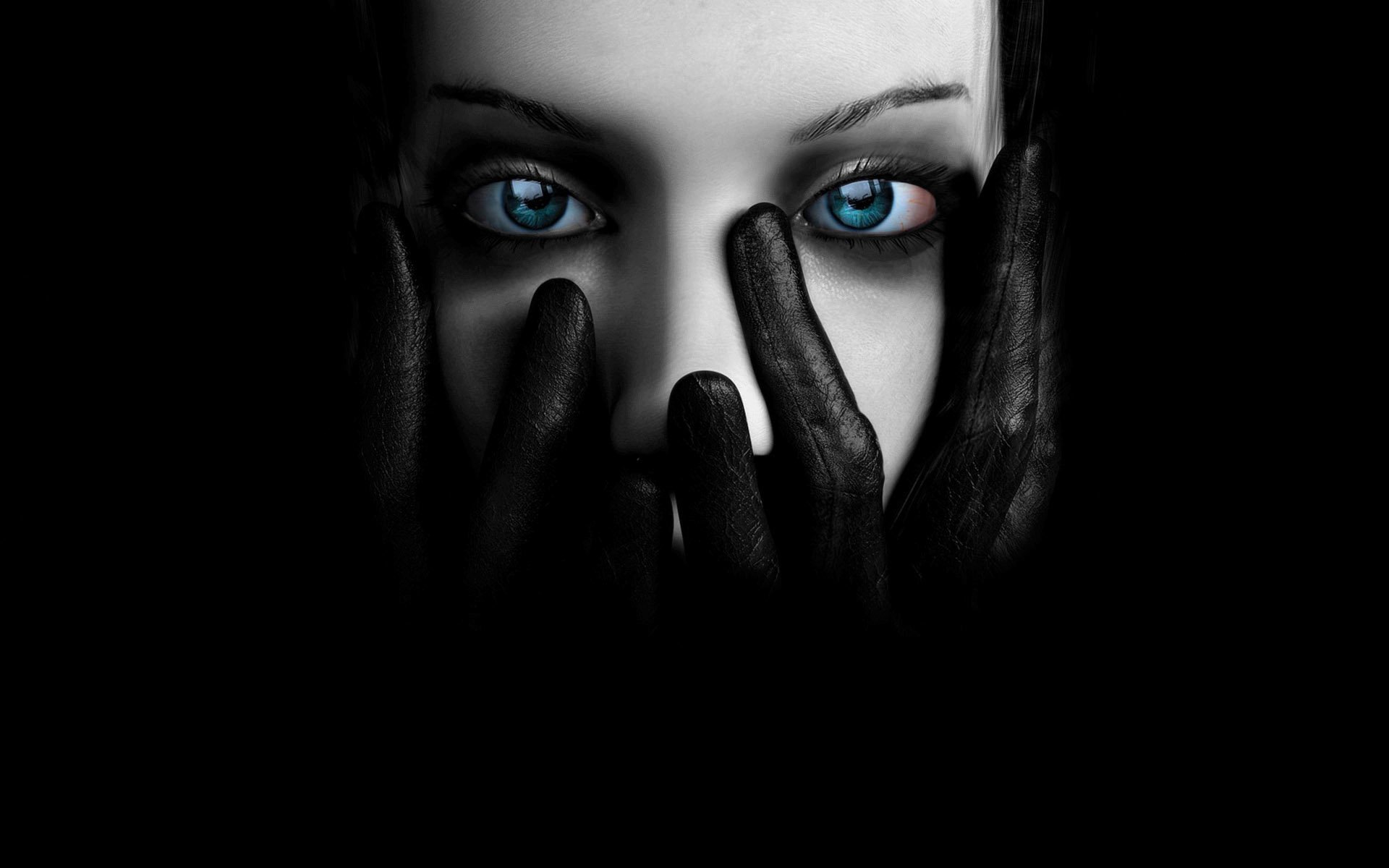 Close-up of a woman in a dark setting, gloved hands partially covering her face, piercing blue eyes visible through the shadows.
