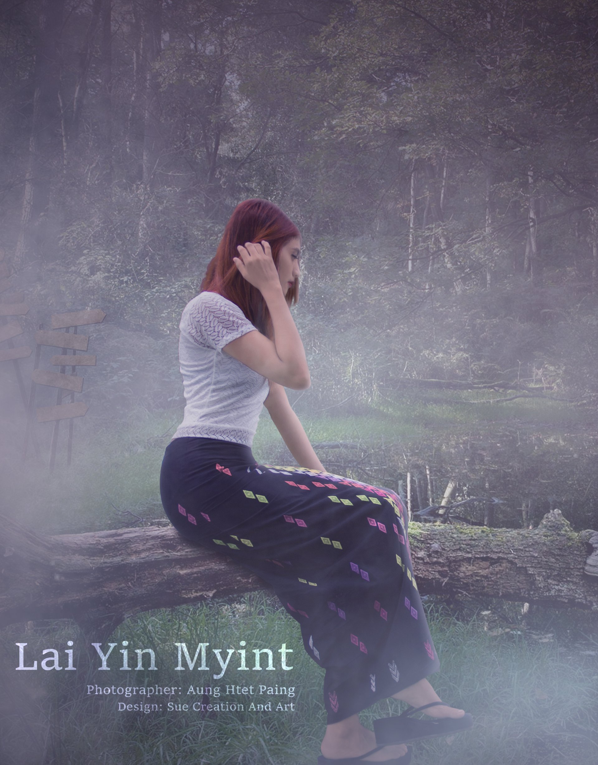 A woman of Asian descent sits contemplatively on a log by a serene water body, wearing a white top and patterned black pants, surrounded by a misty natural setting.