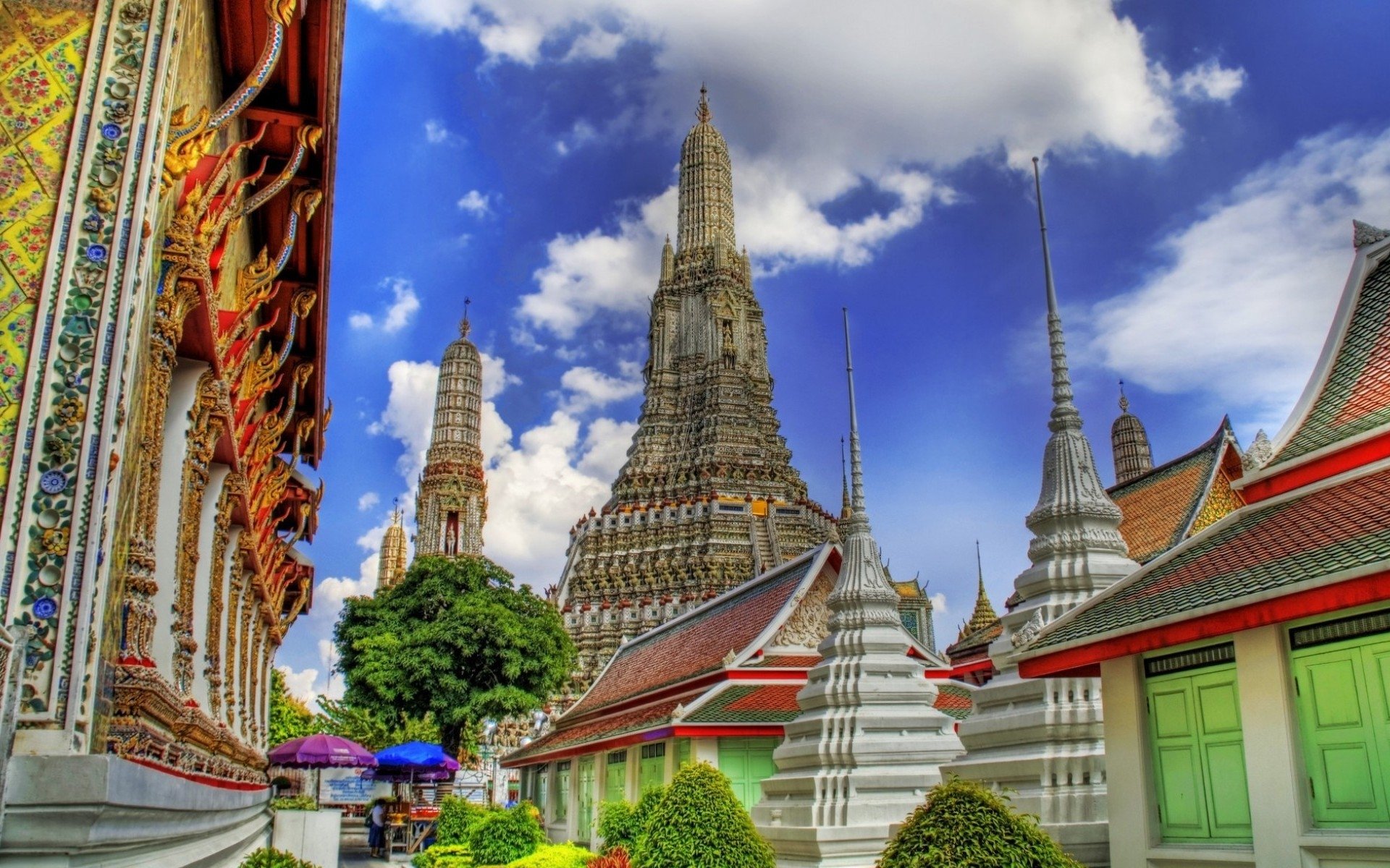 Colorful exterior of Wat Arun Temple with its ornate spires under a vibrant sky in Bangkok, Thailand, showcasing intricate religious architecture.