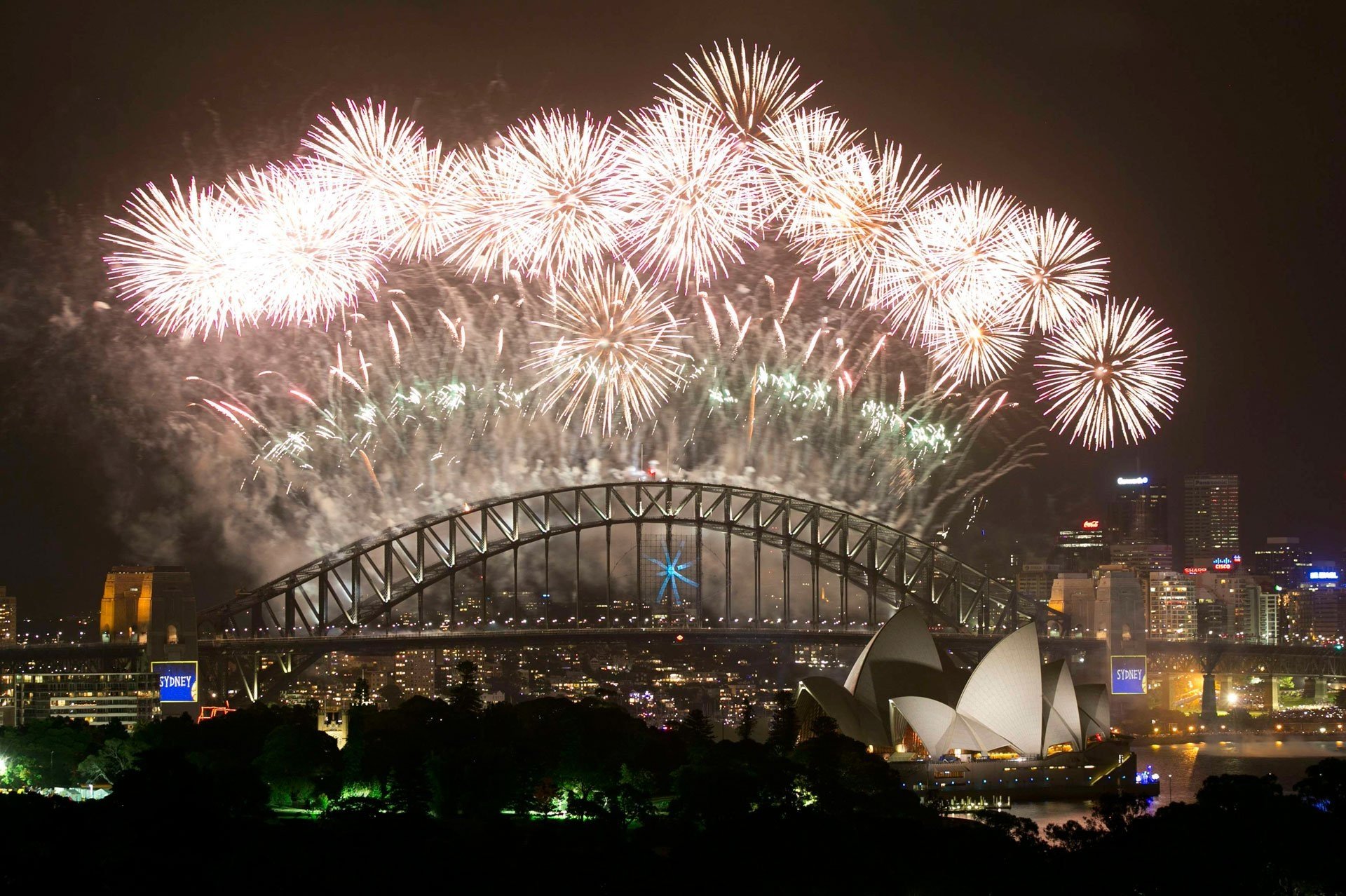 Vibrant fireworks illuminate the night sky over Sydney Harbour Bridge and Sydney Opera House, celebrating New Year's Eve in the heart of the Australian city.