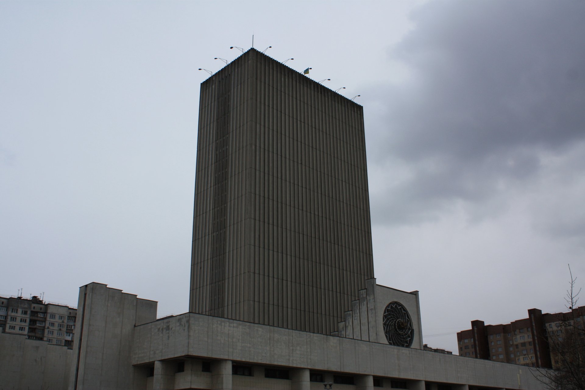Tall concrete library tower in Kiev, Ukraine, rising from a modernist plaza under heavy, overcast skies.