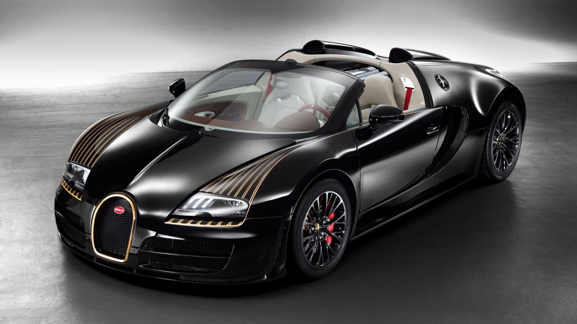 Sleek black Bugatti Veyron Grand Sport Vitesse with distinctive gold accents, showcased under soft lighting emphasizing its luxury and performance design.