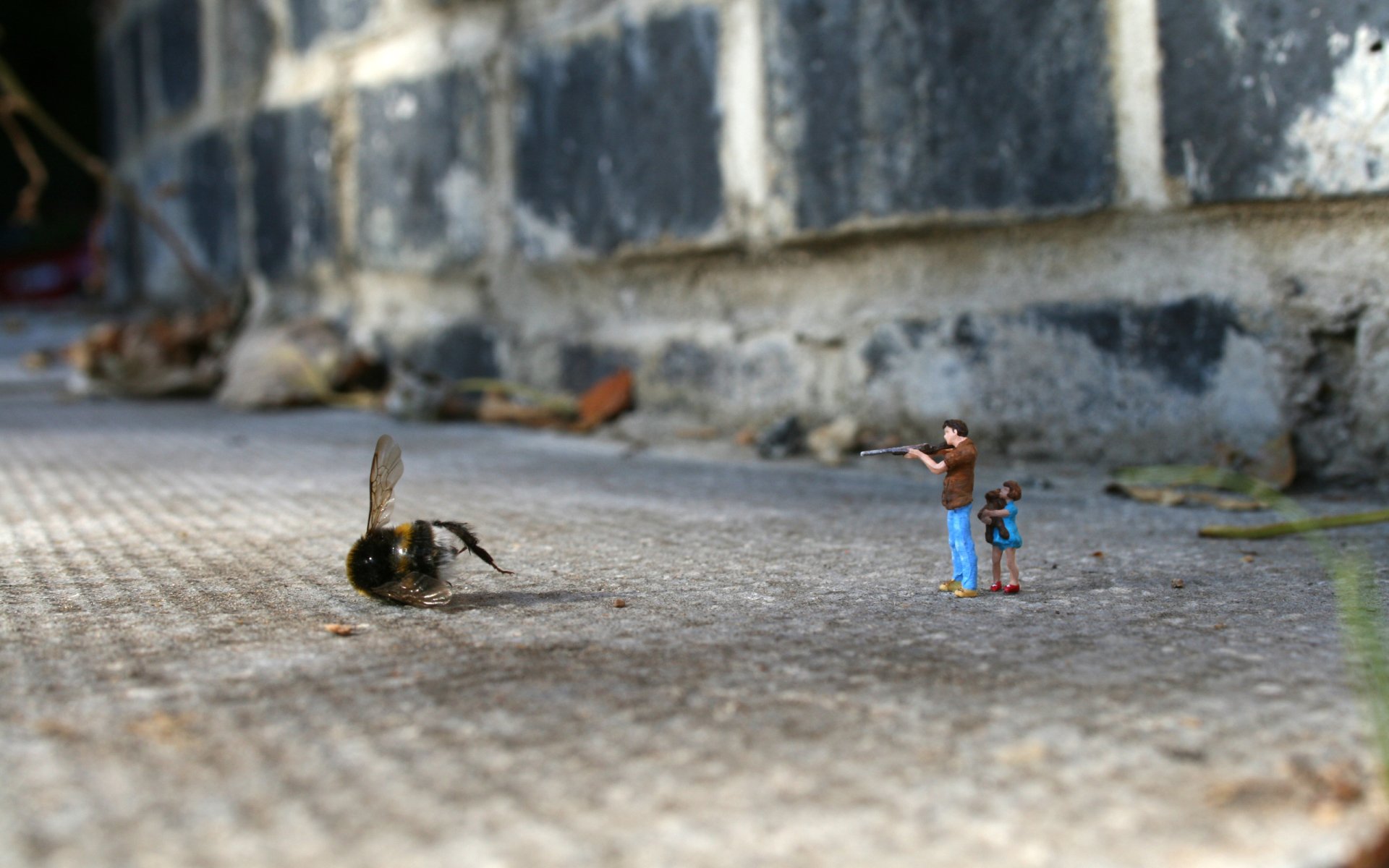 A close-up photograph captures a whimsical scene of tiny figurines interacting with a large bumblebee on a textured surface, highlighting the playful contrast between the two.