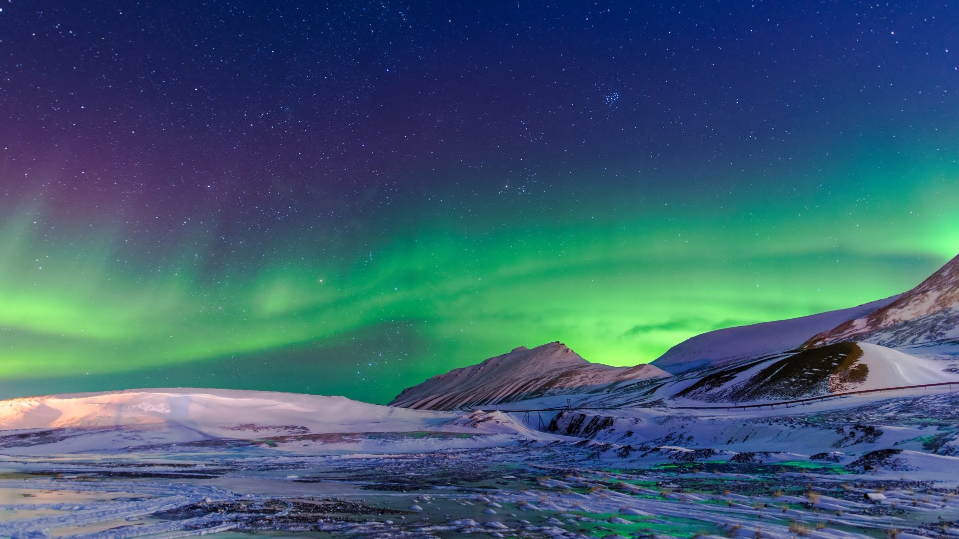 A stunning winter landscape covered in snow, illuminated by the vibrant colors of the aurora borealis dancing across the night sky.