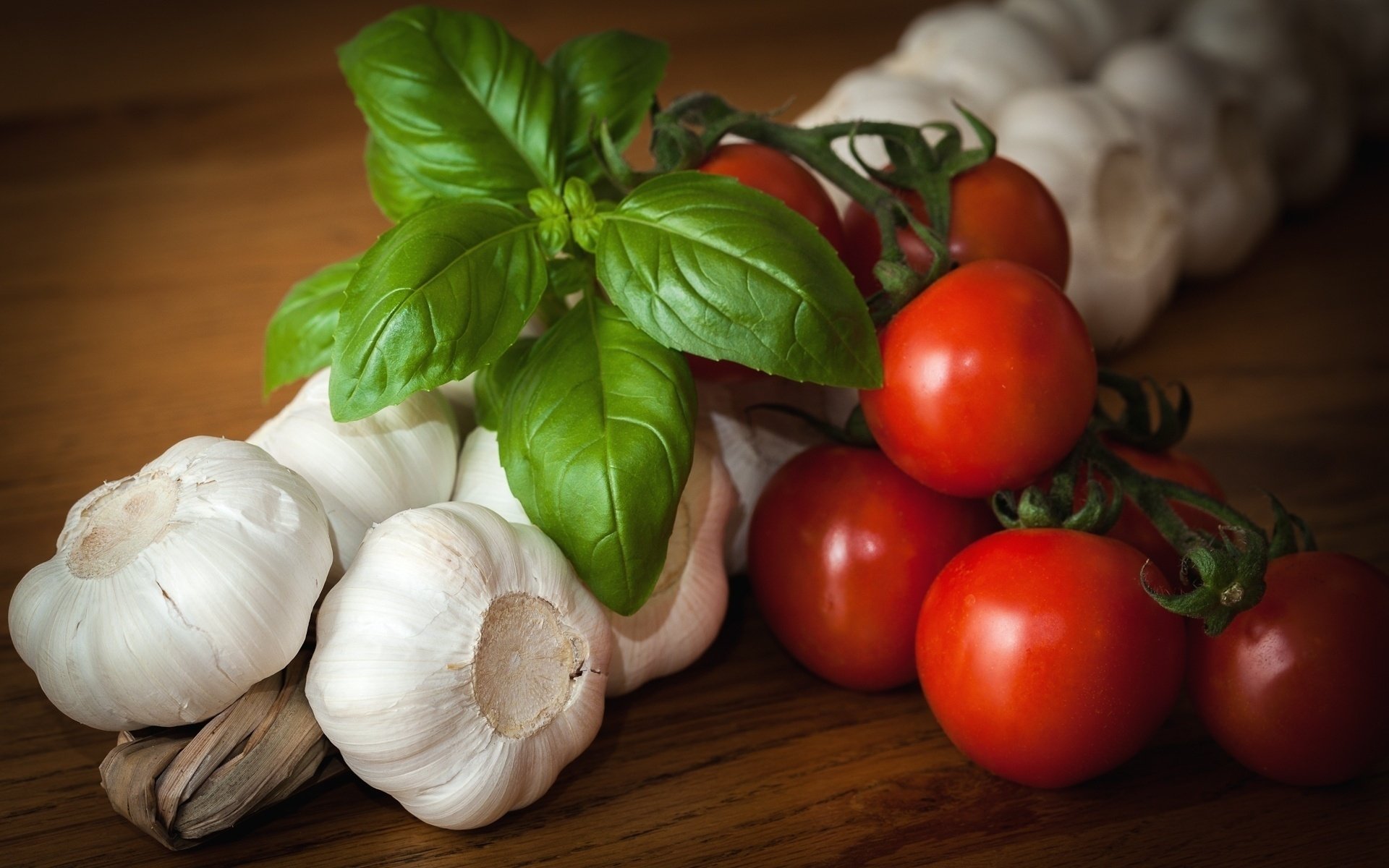 A vibrant arrangement of fresh tomatoes, garlic, and fragrant basil, showcasing a delightful mix of vegetables set against a rustic wooden background.