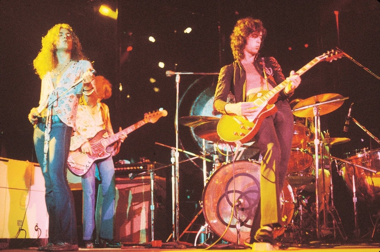 Legendary rock band Led Zeppelin performs on stage, showcasing their iconic music style with vibrant lighting and energetic presence.