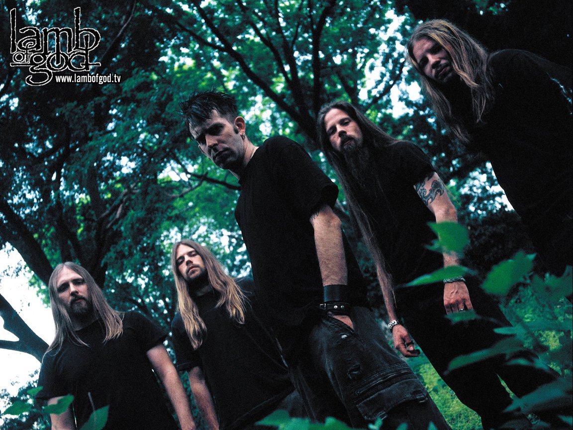 A group of five musicians from Lamb of God stands together in a lush, green setting, embodying the intensity of their metal music, reminiscent of Nickelback's powerful presence.