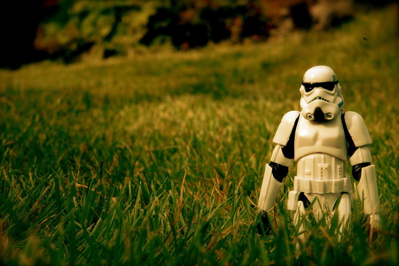 A stormtrooper toy figurine stands alone in a field of grass, capturing the essence of Sci-Fi from the Star Wars universe.