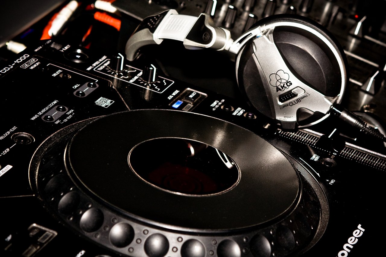 Close-up of a Pioneer DJ turntable and headphones on a mixer under moody lighting — music, Just Music.