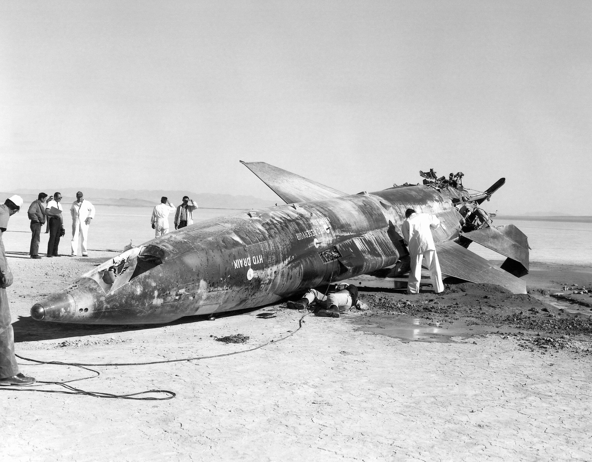 North American X-15 military aircraft resting on the ground with personnel inspecting it after a test flight in a desert environment.