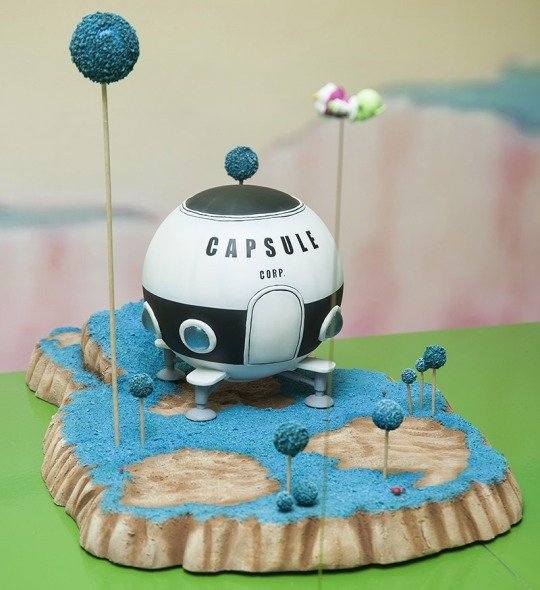 A miniature scene from Dragon Ball Z featuring the Capsule Corporation spaceship on a textured base with colorful trees, capturing the anime's whimsical aesthetic.