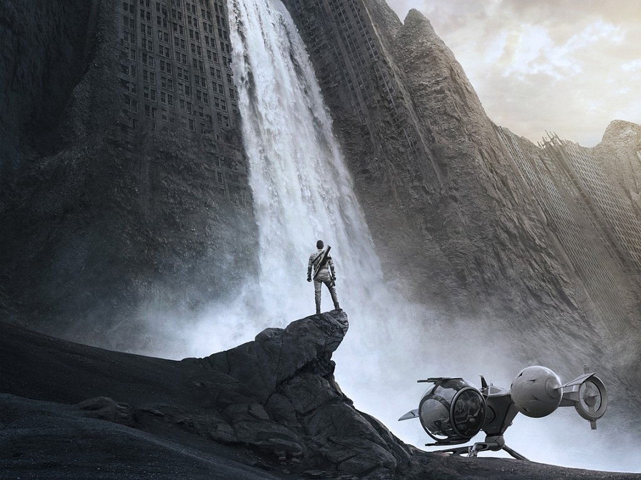 A lone figure stands on a rock cliff beside a futuristic drone, overlooking a massive waterfall cascading down towering cliffs in a scene from the movie Oblivion (2013).