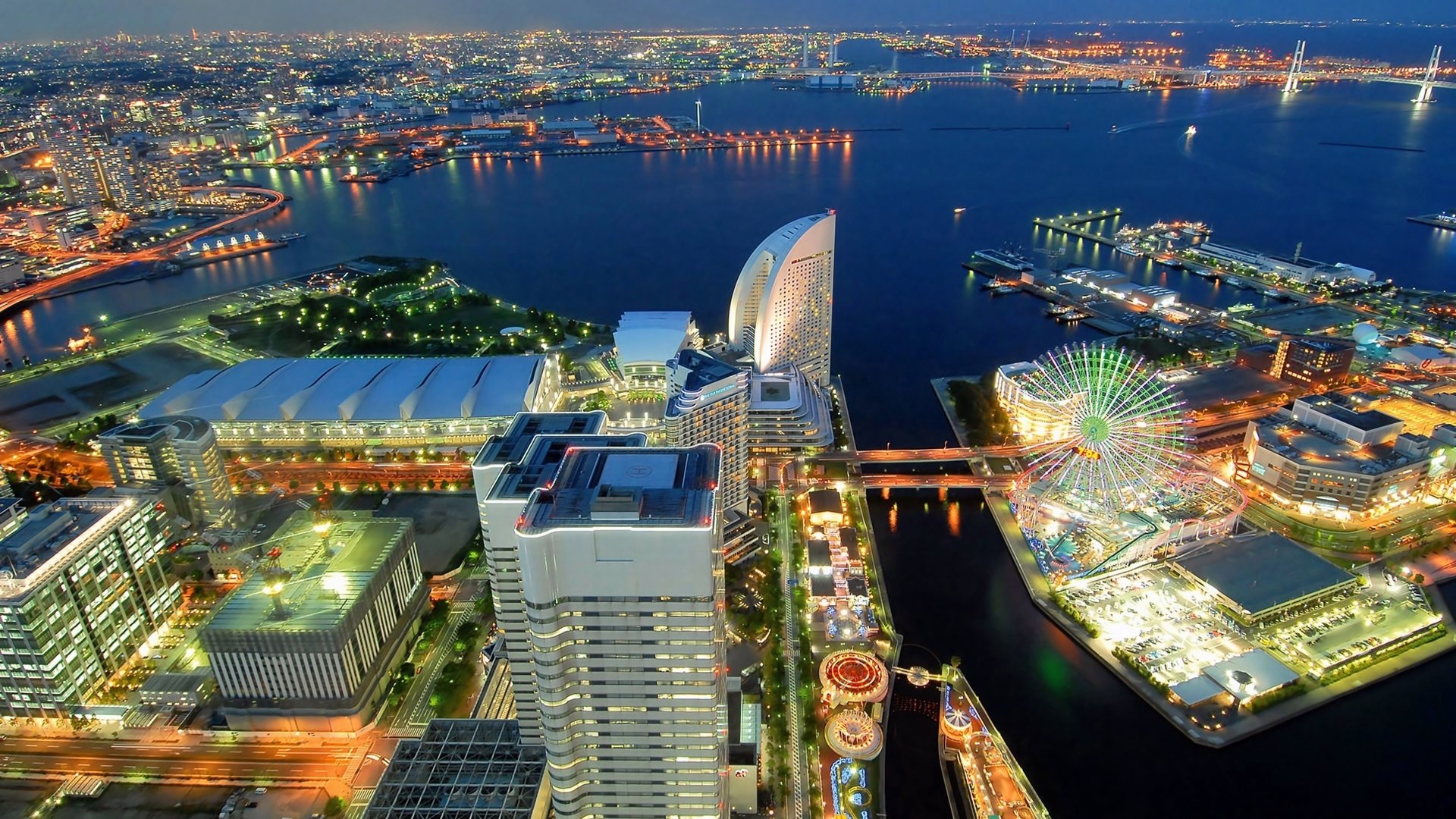 Aerial view of Yokohama, Japan, showcasing a vibrant skyline with modern architecture, waterfront, and amusement areas illuminated at night.