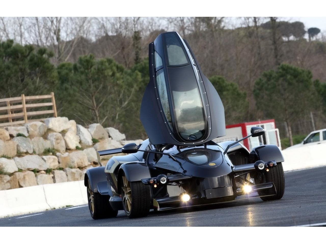 2009 Tramontana R race car: low-slung Tramontana vehicle on track with butterfly-style canopy raised and headlights on.