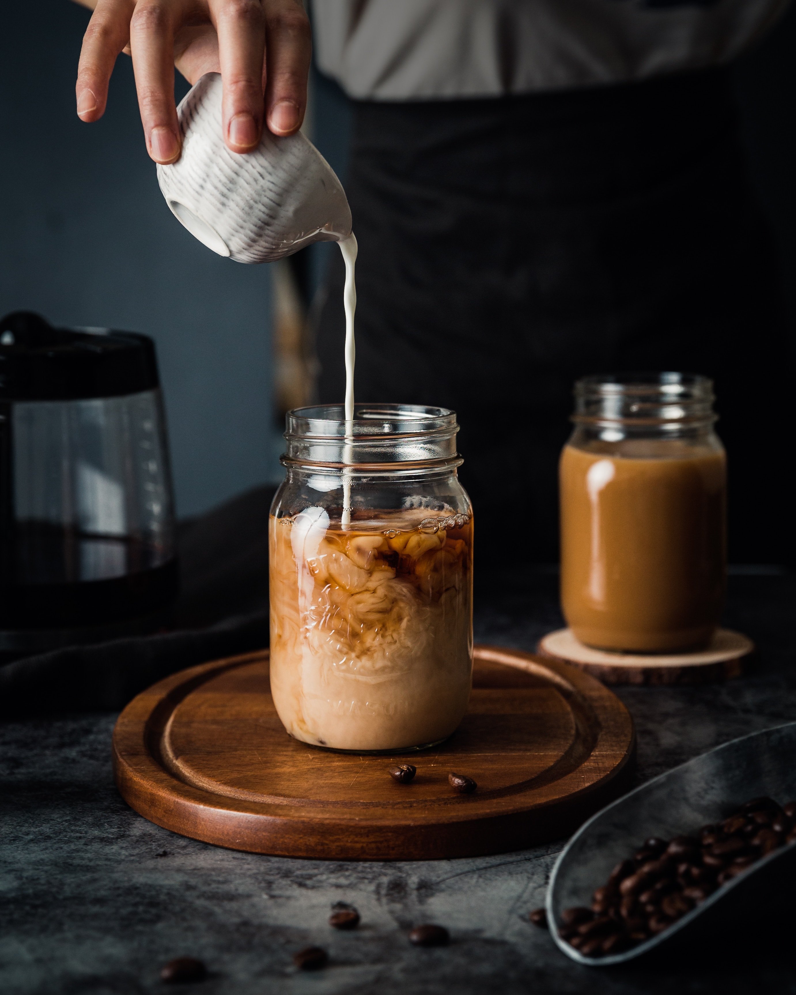Pouring milk in a jar with coffee by Mae Mu