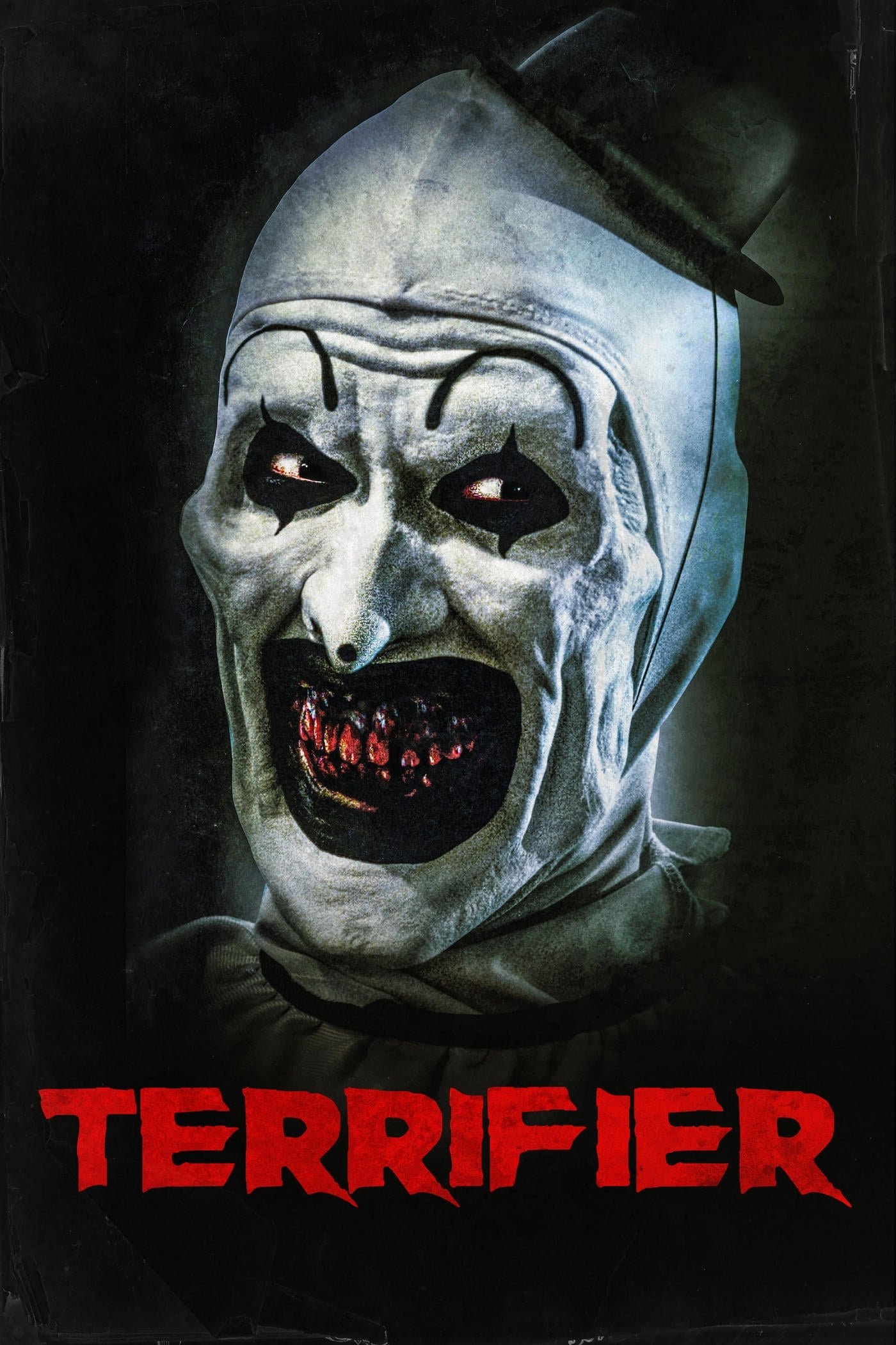Grotesque white-faced clown with dark eye makeup and bloodied teeth looming from shadow, bold red TERRIFIER movie title across the bottom.