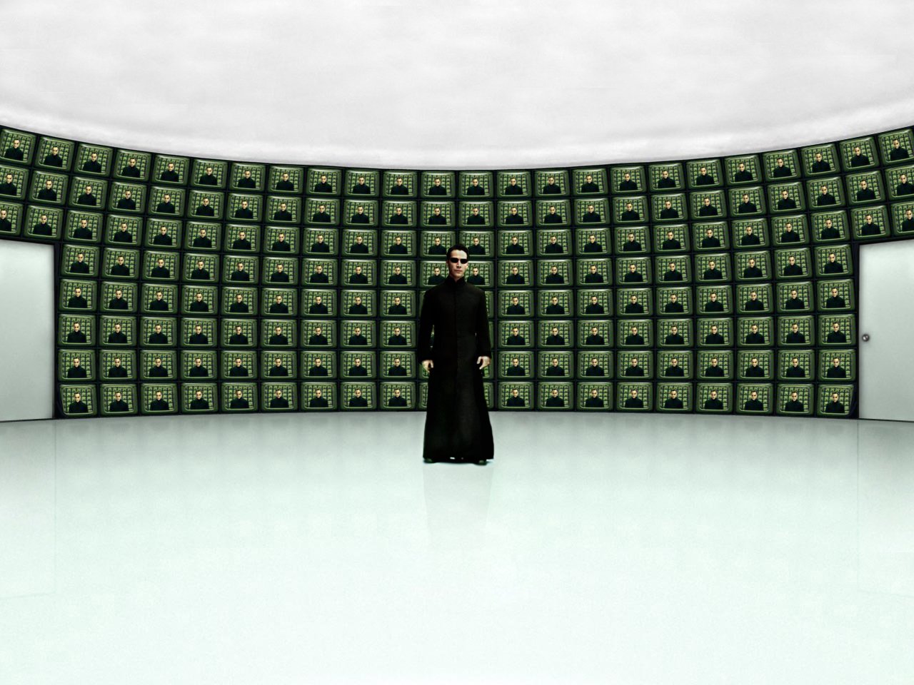 Neo, portrayed by Keanu Reeves, stands in a minimalist room surrounded by numerous green-tinted screens, evoking the iconic visuals from the movie The Matrix.