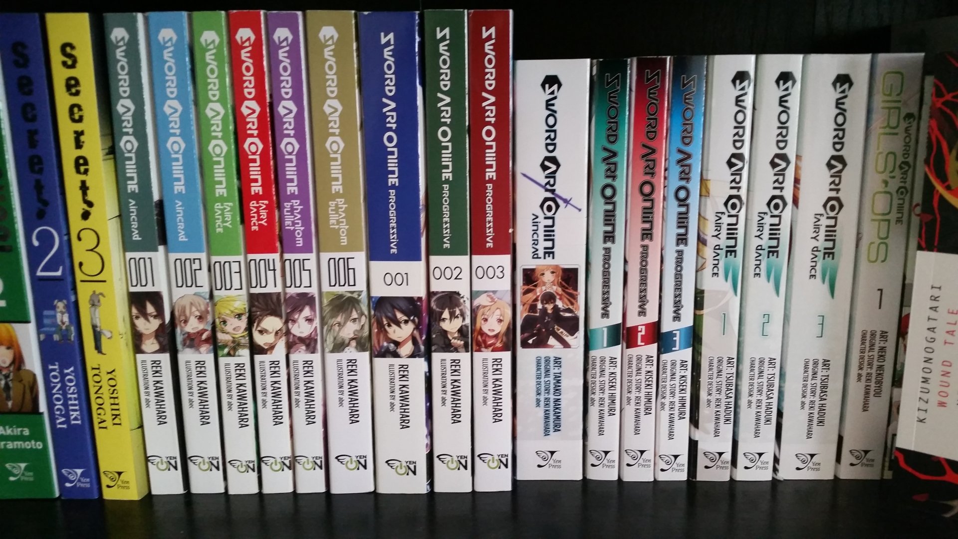 A collection of Sword Art Online manga volumes displayed on a shelf, alongside other anime books, showcasing the series' distinctive covers and numbering.