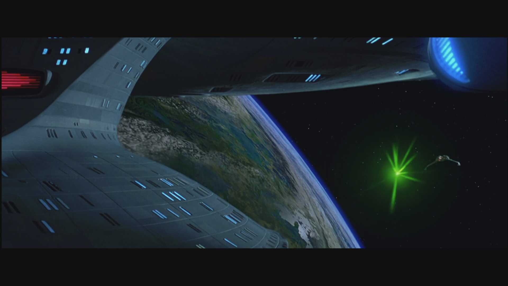 Scene from the movie Star Trek Generations showing a spaceship near a planet with a glowing green energy blast in space.