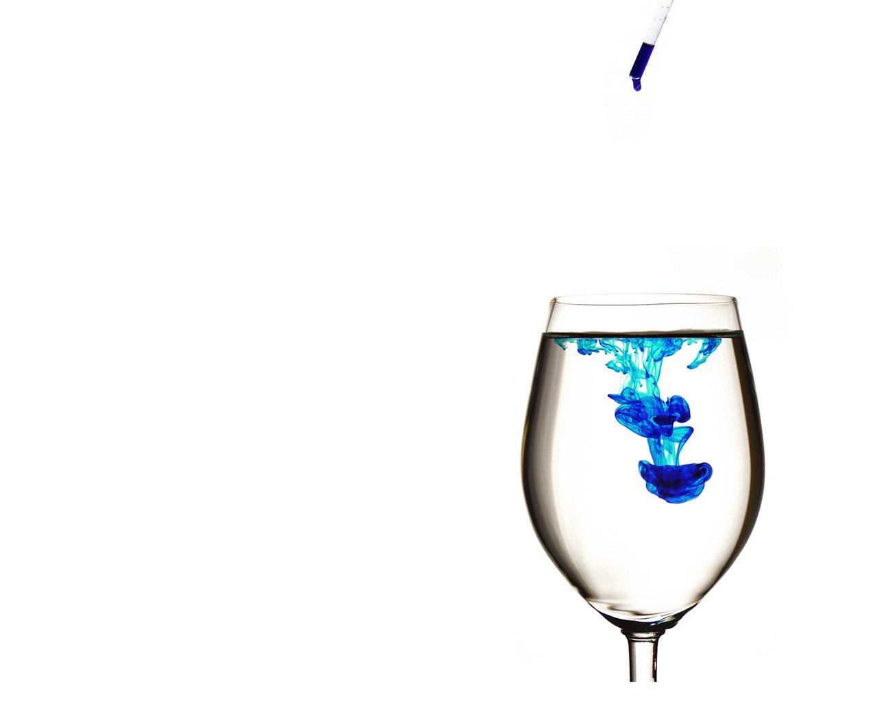 A glass of water captures swirling blue ink, showcasing an artistic interplay of liquid elements. The vibrant color contrasts beautifully with the clear water.