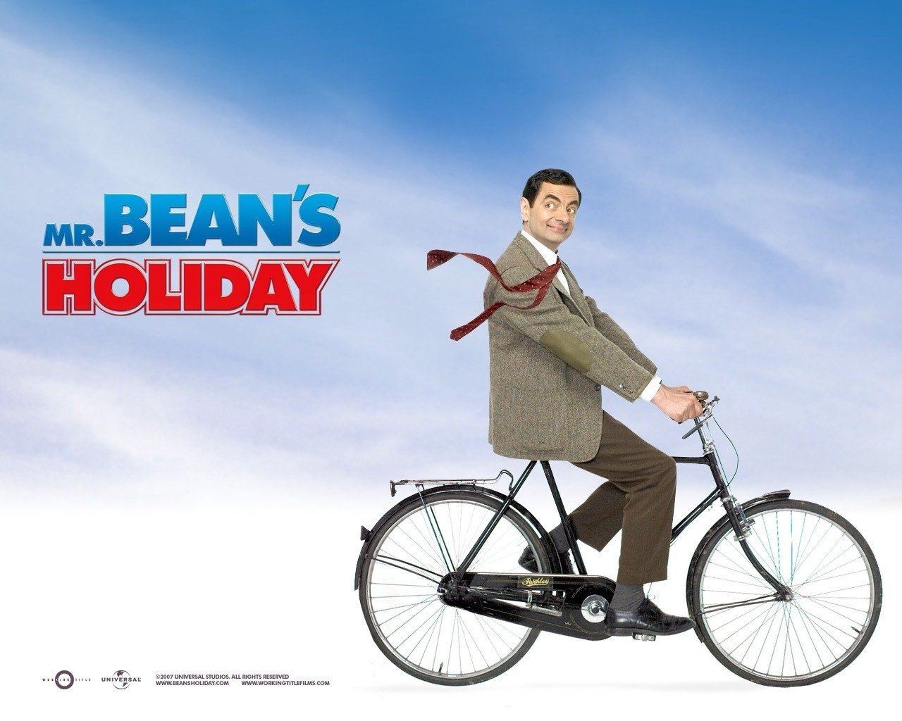 Mr. Bean rides a bicycle with a playful expression against a bright blue sky, promoting the whimsical spirit of the movie Mr. Bean's Holiday.