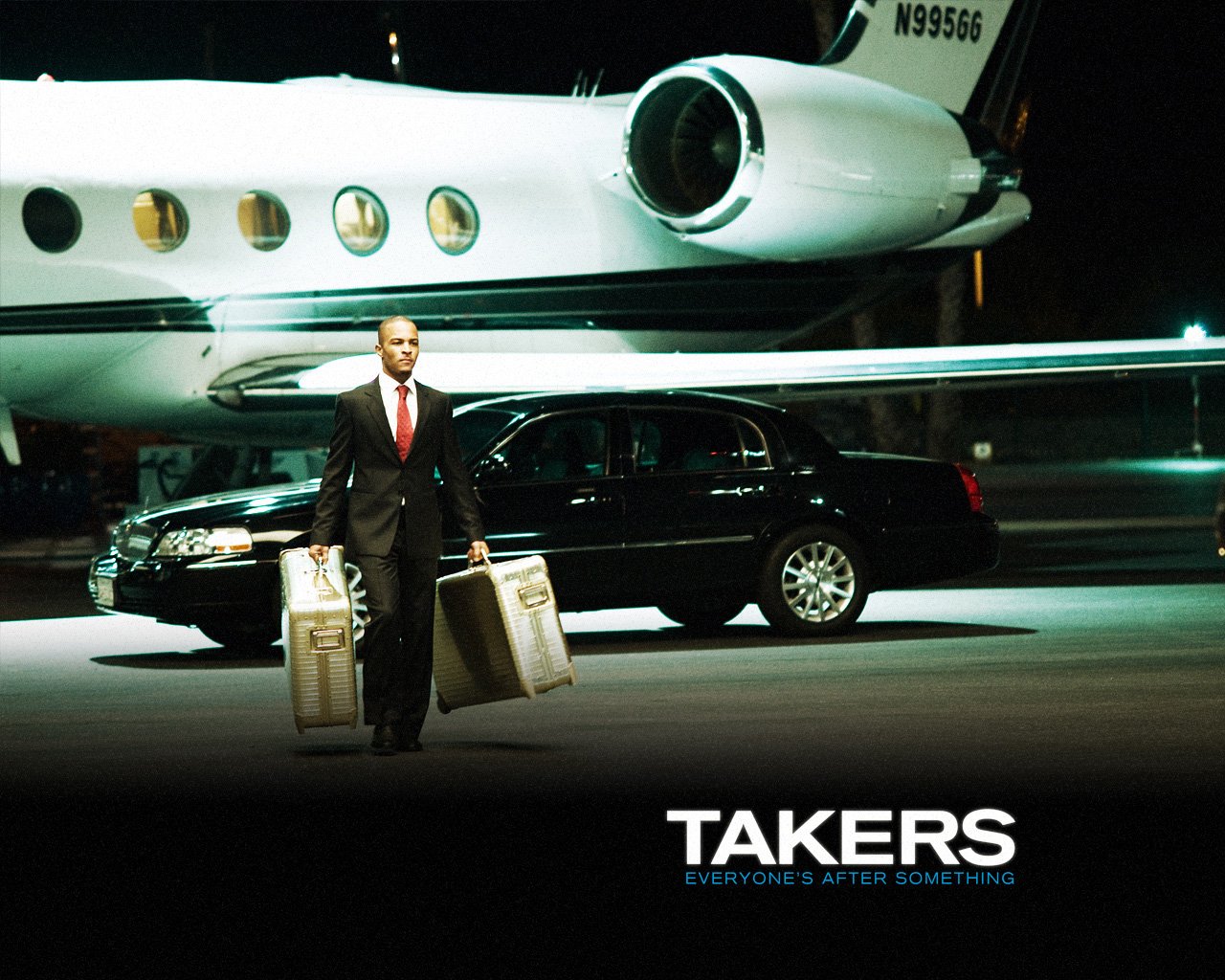 A man in a suit walks on an airport tarmac carrying two briefcases with a private jet and black car behind him, from the movie Takers.