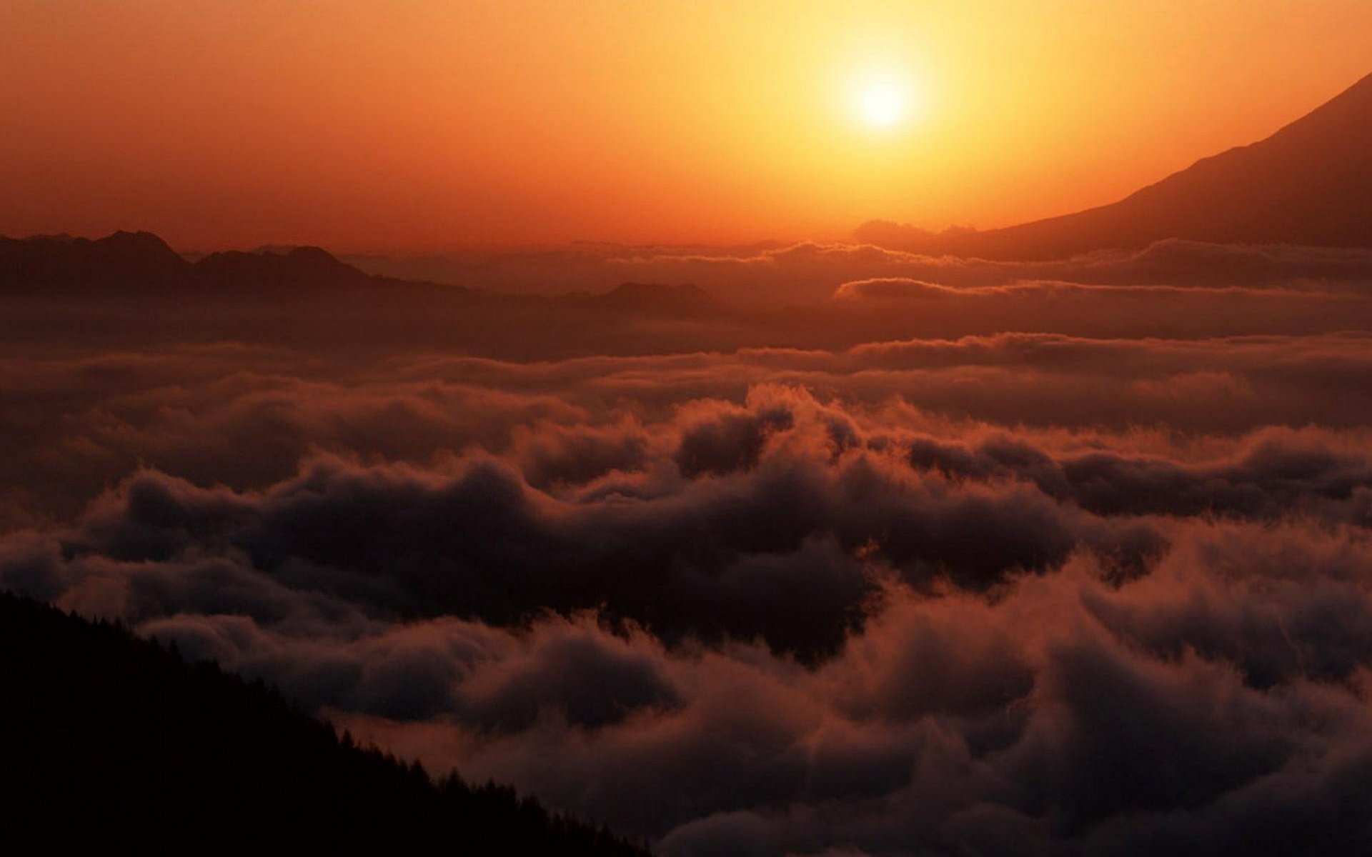 Sunset over a sea of clouds blanketing mountainous terrain, showcasing the serene beauty of nature.