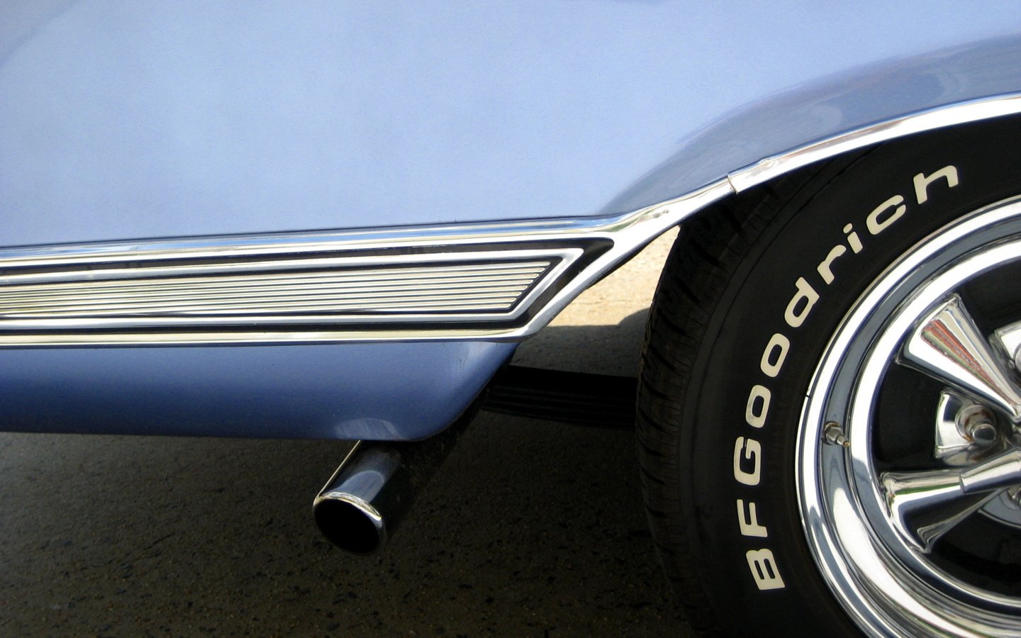 Close-up of a blue vehicle rear quarter showing a chrome exhaust pipe, polished wheel and BFGoodrich tire lettering.