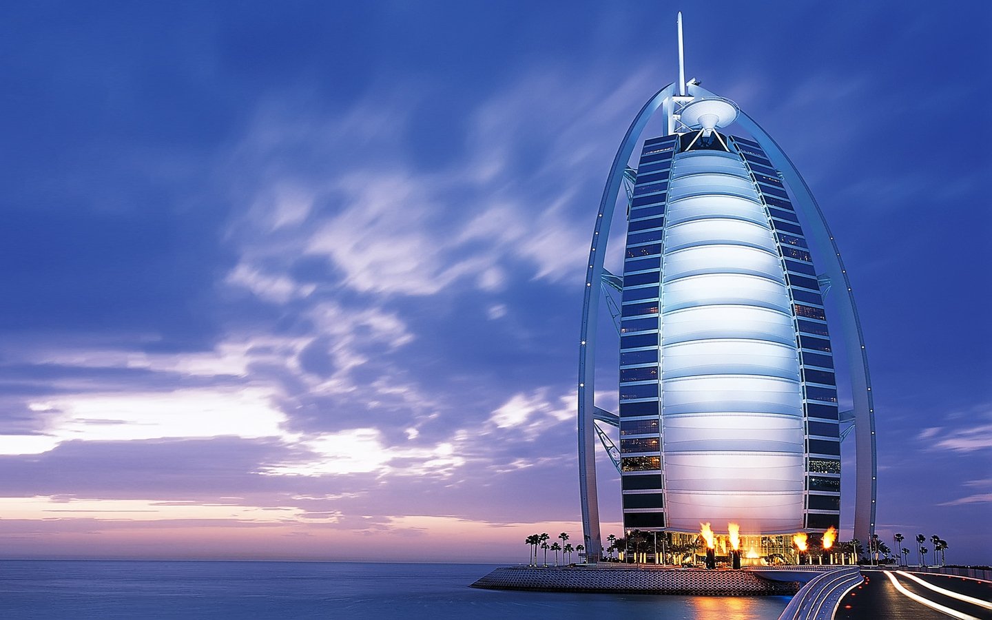 The Burj Al Arab, a man-made architectural icon, stands illuminated against a twilight sky in Dubai.