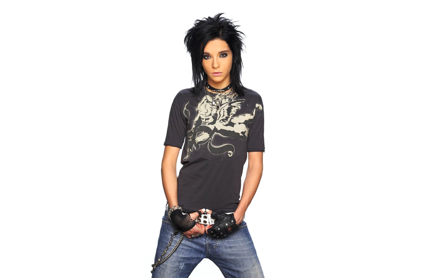 Portrait of a Tokio Hotel band member in casual rock attire, posing confidently against a white background.
