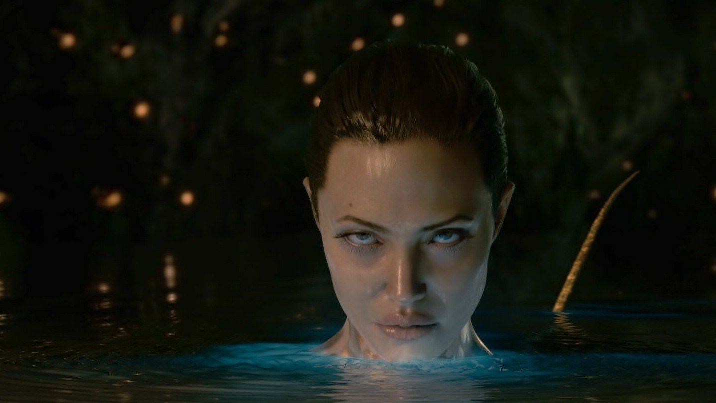 Angelina Jolie emerges from water in a dramatic scene from the movie *Beowulf* (2007), her intense gaze highlighted by the shimmering blue light around her.