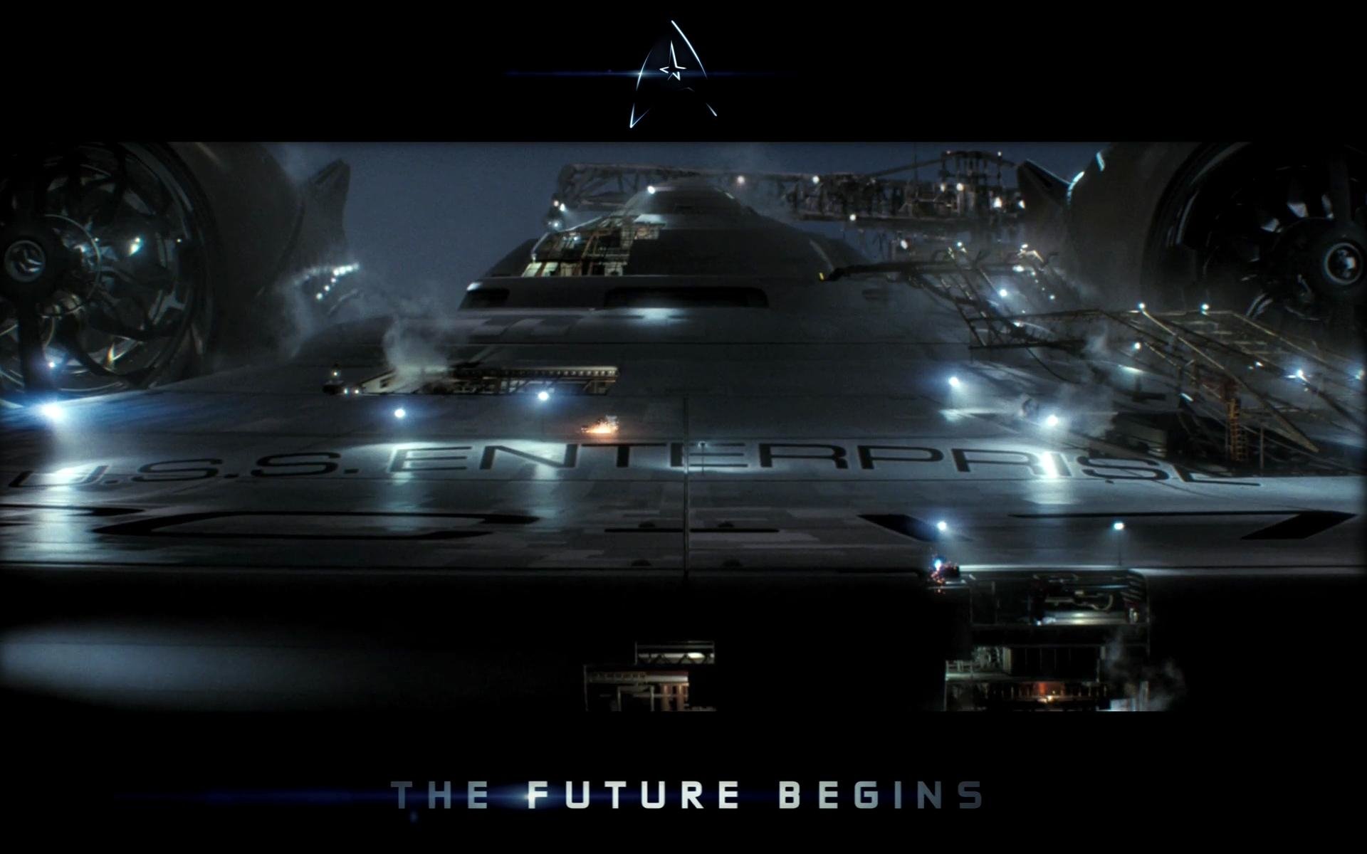 The starship Enterprise (NX-01) from the Star Trek movie is shown docked, illuminated against a dark background with the caption The Future Begins.