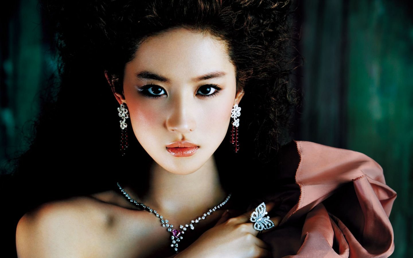 A close-up portrait of a woman with striking features, wearing elegant jewelry, featuring Liu Yifei with voluminous hair and a captivating expression.