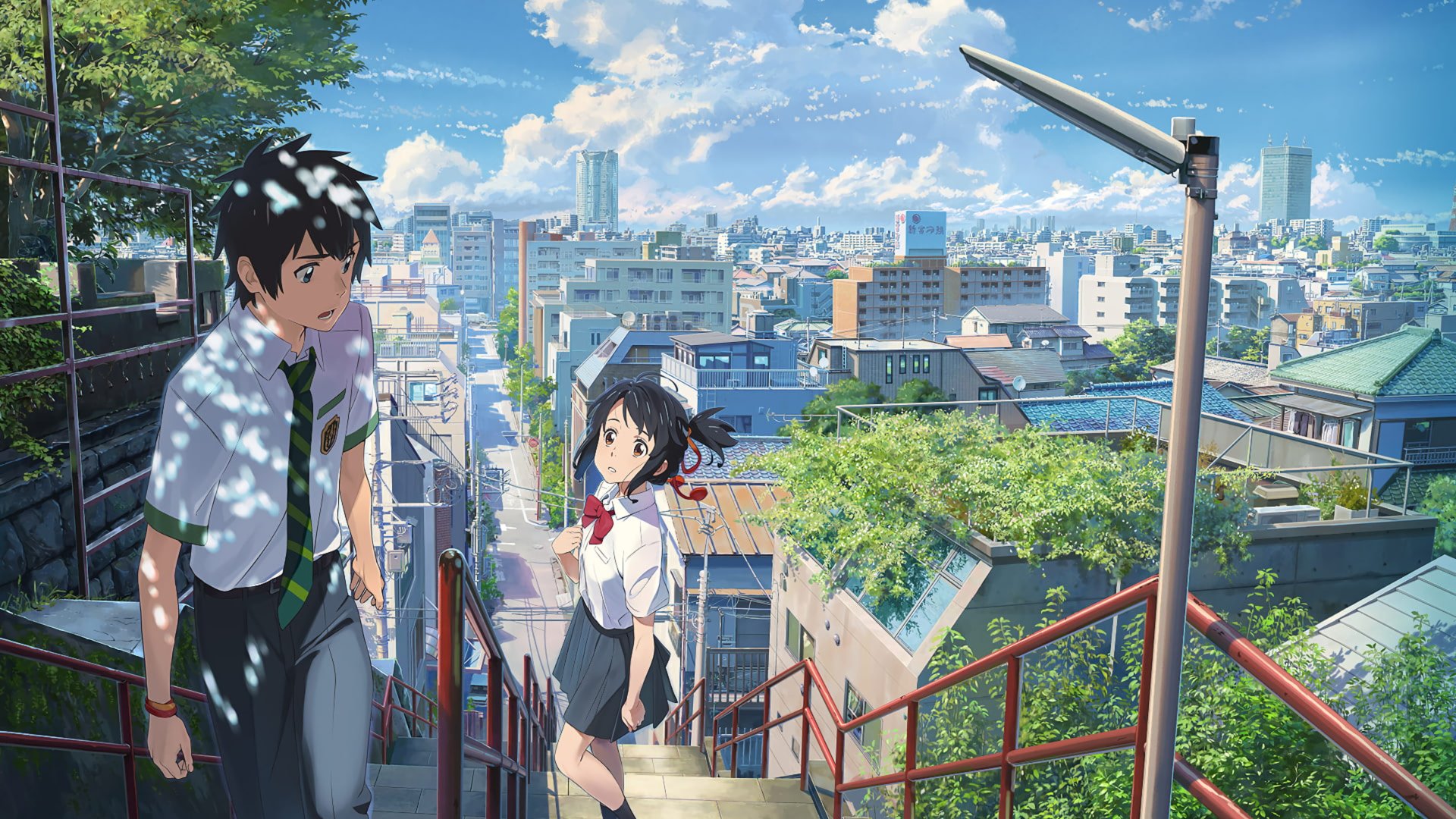 Scene from the anime Your Name., showing two students on a stairway overlooking a detailed cityscape under a bright blue sky.