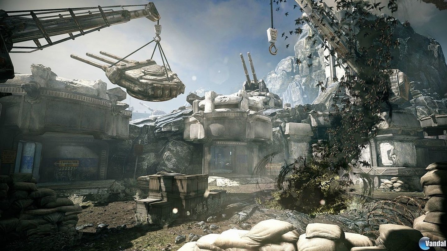 A battlefield scene from the video game Gears of War: Judgment, featuring armored vehicles, sandbags, and a rugged, war-torn environment.
